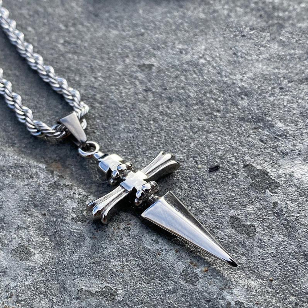 Silver necklace with a cross and spike pendant on a textured surface