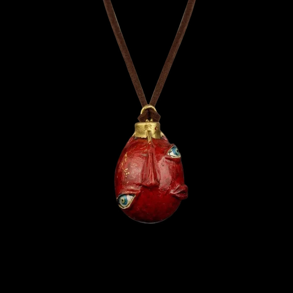 Red stone pendant with gold accents on a dark background