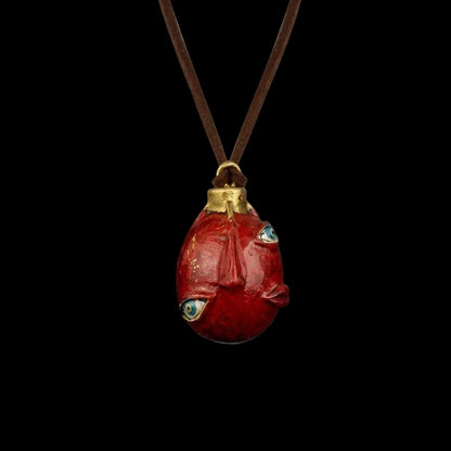 Red stone pendant with gold accents on a dark background