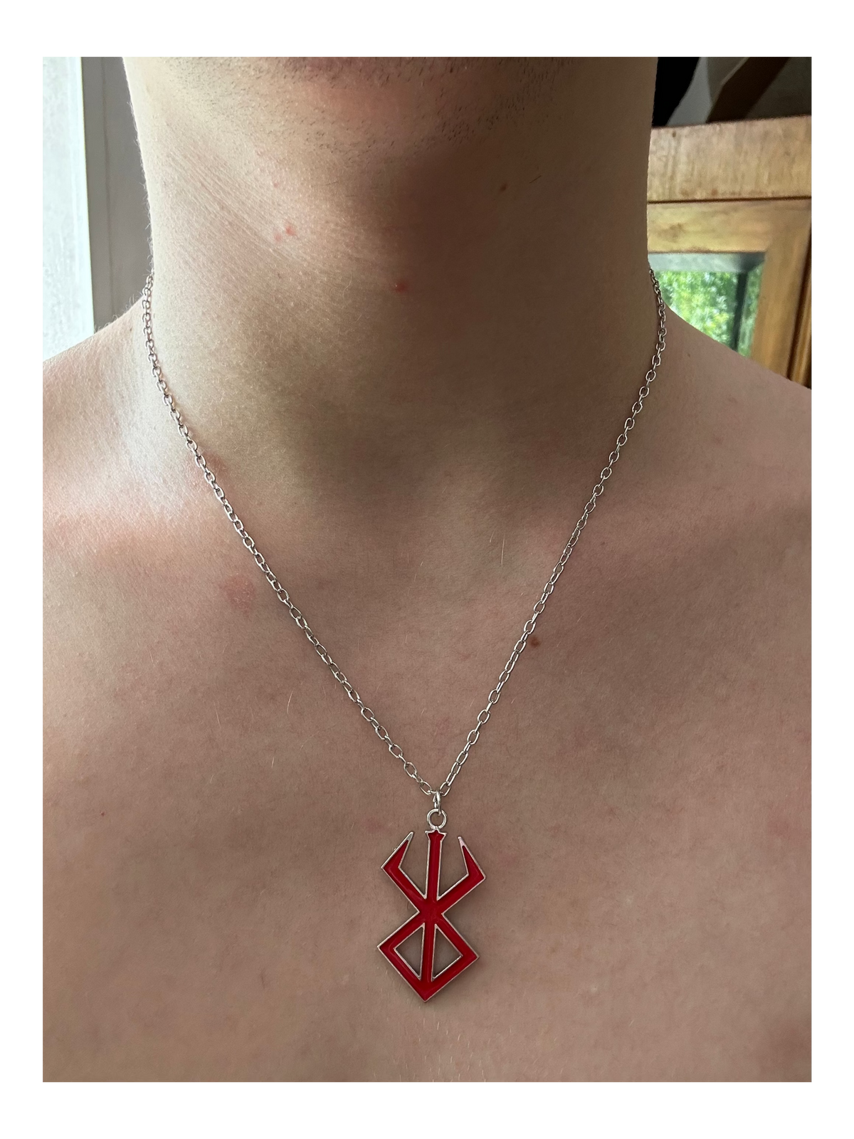 Red pendant necklace on a person's neck with a neutral background