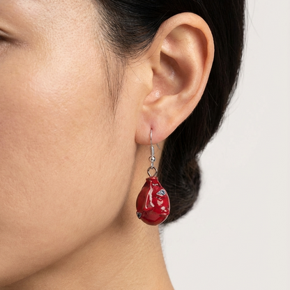 Close-up of a person wearing a red teardrop earring with a white background