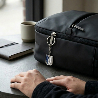 Black travel bag with a keychain on a table next to a notebook