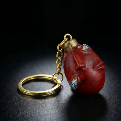 Red stone keychain with gold chain on a dark background