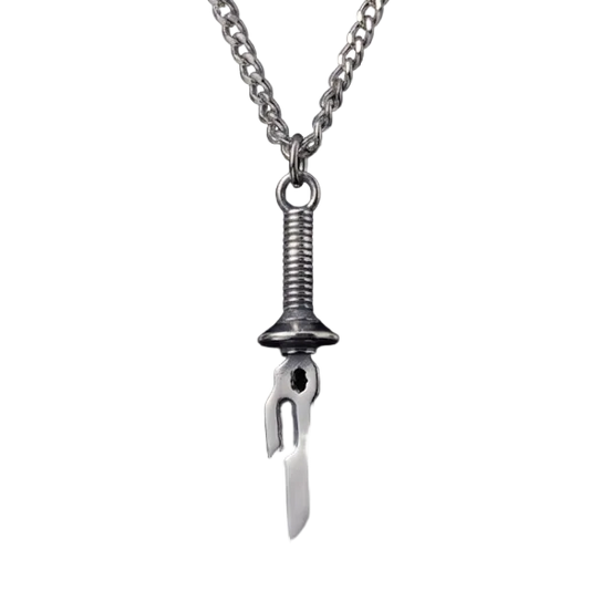 Metallic pendant necklace on a reflective black surface with a dark background