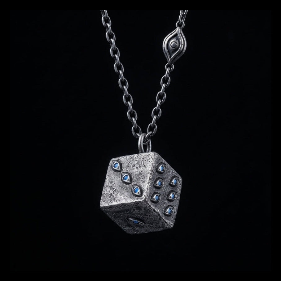 Silver dice-shaped pendant with blue gemstones on a black chain against a black background