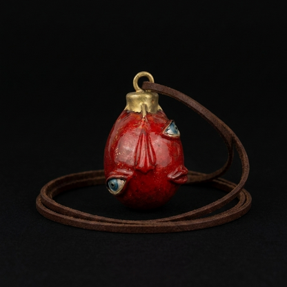 Red fish-shaped pendant on a brown cord against a black background